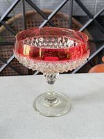 Full view of cranberry and clear glass compote bowl on pedestal