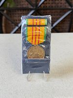 Front view of medal with ribbon and ribbon bar in sleeve
