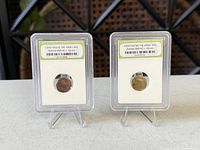 Two slabbed Roman coins on stands, front view
