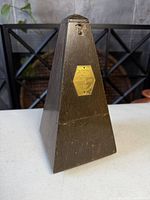 front view of wood pyramid metronome with brass plaque