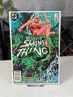 Front cover of Swamp Thing #25 in sleeve and board