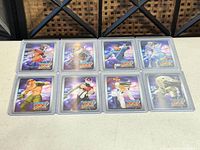 Eight holographic trading cards in top loaders displayed on table