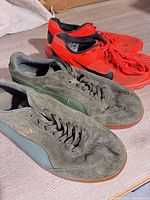 Two pairs of men’s athletic shoes: green Puma Liga and red Nike running shoes