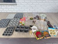 Full lot overview with muffin tins, drink markers, glassware, ice bucket, cake dome, pocket pie molds, linens