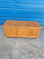 Front view of wooden storage chest, paneled front, closed lid
