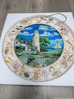Front view showing entire suncatcher with seashell frame and lighthouse artwork