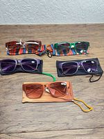 Five pairs of sunglasses laid out showing frames, lenses, and pouches