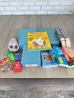 Lot overview showing four blue doll boxes, books, card decks, dice, toy
