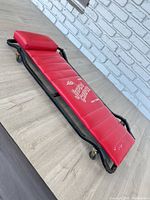 Top view showing full creeper, red padding, headrest, frame and casters