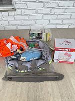 Overview of lot showing dog tunnel, plush bird, wire rings, boxed items, and metal rack