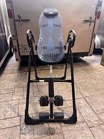 Front view of Teeter inversion table showing full frame, blue perforated backrest, ankle supports