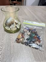 Vase with geode fragments beside bag of polished stones