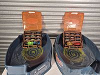 Two Bolt Blast stadiums each holding an orange compartment case filled with tops