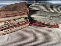 Two stacks of folded decorator fabric remnants in assorted patterns and colours