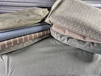 Stack of mixed upholstery fabrics showing various colors and patterns