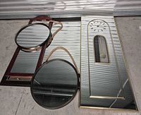 Group shot of four wall pieces: rectangular mirrored pendulum clock, wood mirror panel, two round brass-framed mirrors