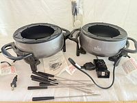 Overview of both Rival fondue pots with cords, forks and manuals