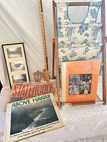 Group shot of lot showing books, poster, triptych, carved decor, folding rack