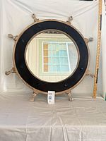Front view of round ship wheel mirror with ruler for scale