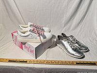 Both pairs of sneakers side by side with ruler for scale
