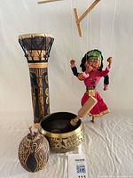 Group shot of all four items: singing bowl with striker, Balinese drum, puppet, carved gourd