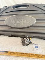 Gun case front with Flambeau logo and fishing reel for scale