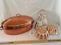 Group shot showing roasting pan with lid and rack alongside four vintage molds