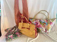 Group shot showing all four bags: yellow ostrich satchel, floral tote, pleated sling, floral pouch