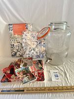 Full lot overview: glass dispenser, packaged tablecloth, folded linen, serving tray with plates