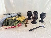 group shot of all items: four candle holders, scarves stack, metal bird, letter opener