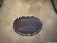 Close-up of oval leather patch embossed "TV Land" on bag side