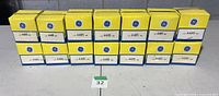 Front view of 14 boxed GE 4405 pinspot lamps aligned on table