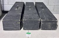 three black wooden road cases side by side, lids on