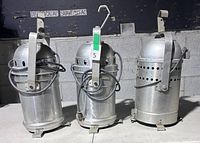 Front view of three aluminum PAR 64 cans showing yokes, clamps and cords