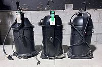 Front view of three black PAR 64 cans with cords, clamps and base plates
