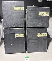 Stack of four black wooden road cases showing tape labels and wear