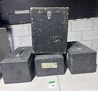 Four black wooden road cases stacked, showing handles and latch