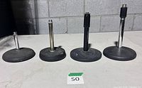 Four tabletop microphone stands lined in a row showing bases and shafts