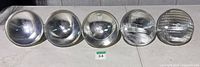 Front view of five PAR64 bulbs showing three smooth narrow-spot lenses and two ribbed flood lenses