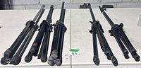Five collapsed tripod microphone stands laid out on a table