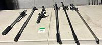 Six assorted microphone boom arms laid out showing finishes and lengths