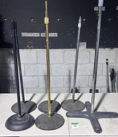 Six straight microphone stands with various heavy bases on table