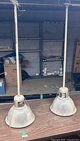 Two pendant lights on table showing full length rods and glass domes
