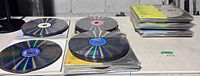 Stacks of karaoke LaserDiscs in various sleeves and loose on table