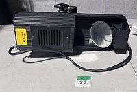 Left side view of Lumi LE-122 moonflower light effect showing housing, vent grille, mounting knob, power cord and mirrored output disc