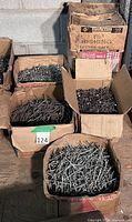 Overview of six open boxes filled with assorted nails of varying sizes