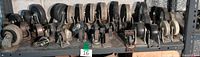 Shelf row of large plate-mount casters in metal yokes with black wheels