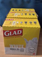 Three sealed Glad Guaranteed Strong White Small 25 L 100-bag boxes in a row