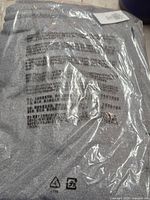 Front of sealed package showing grey sweatpants and multilingual warning text