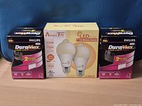 Front view of two Philips DuraMax vanity bulb boxes and AmeriTop LED motion-sensor bulb two-pack